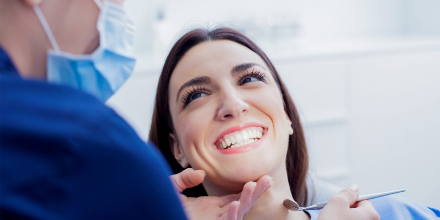 Frau ohne Periimplantitis lächelt Zahnarzt an.